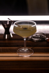 cocktail with garnish in angled crystal coupe cocktail glass on wooden cutting board