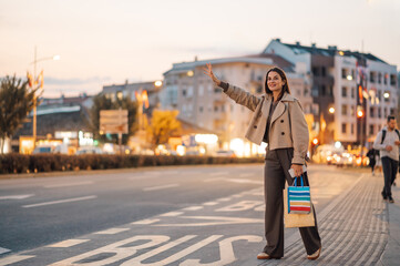 Elegant woman hailing a taxi after shopping spree in the city