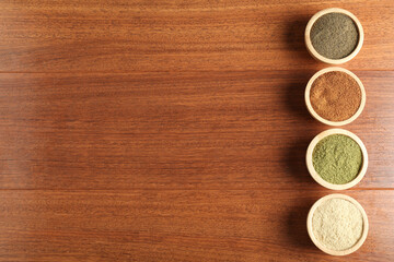 Different superfood powders in bowls on wooden table, flat lay. Space for text