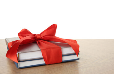 Books with ribbon as gift on wooden table against white background, space for text