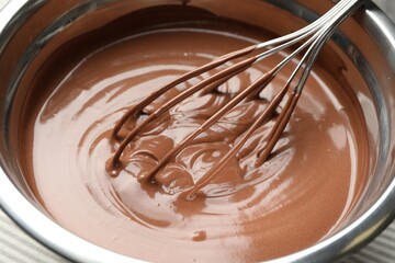 Chocolate dough and whisk in bowl on table, closeup