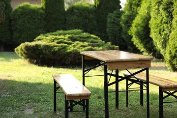 Wooden table with benches in garden on sunny day