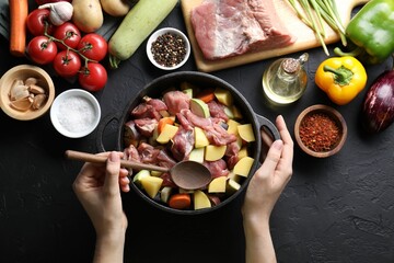 Cooking stew. Woman with uncooked meat, vegetables and pot on black table, top view