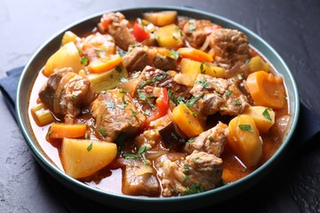 Delicious stew with vegetables on black table, closeup