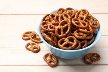 Tasty pretzel crackers on light wooden table, closeup