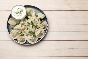 Delicious pelmeni with green onion served on wooden table, top view. Space for text