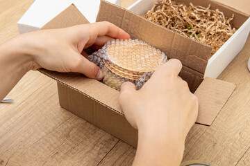 Man packs cosmetics for delivery. Jar of cream, bubble wrap and box. Order collector or packer....