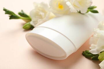 Solid deodorant and beautiful eustoma flowers on beige background, closeup
