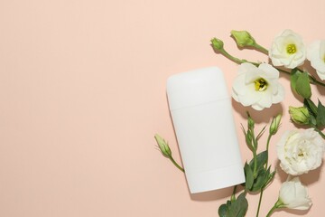 Solid deodorant and beautiful eustoma flowers on beige background, flat lay. Space for text