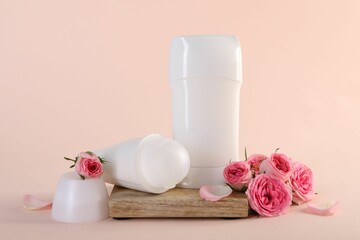 Different deodorants and beautiful rose flowers on beige background