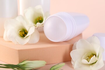 Roll-on deodorant and beautiful eustoma flowers on beige background