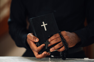 Priest holding holy bible and rosary beads