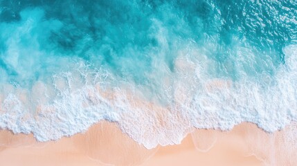 High-altitude view of a clear blue ocean with gentle waves and a bright, sandy beach under sunny weather