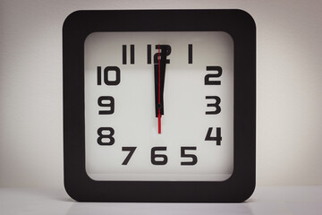 Stationary square analog clock with hands at noon