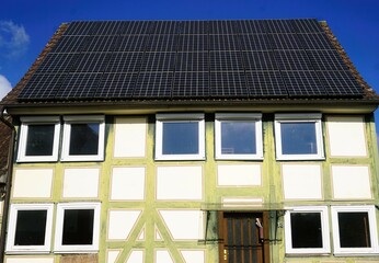 Fototapeta premium Altes Fachwerkhaus mit neuen Fenstern und Solardach bei Sonne am Morgen im Herbst