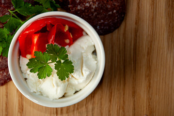 Smoked sausage, cow cheese, fresh peppers, and parsley arranged on a cutting board.