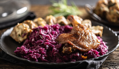 Portion of roast duck leg red cabbage homemade dumplings on plate and red wine on the background © weyo