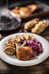 Portion of roast duck leg red cabbage homemade dumplings on plate and red wine on the background