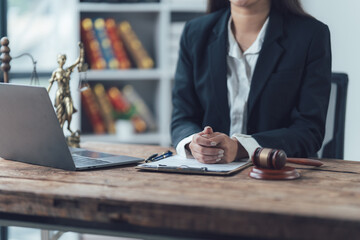 Lawyer at Work: A confident female lawyer in a black suit sits at her desk, focusing intently on a...