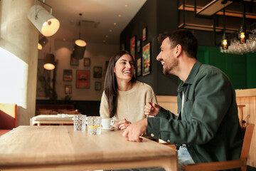 Joyful coffee conversation between friends in a cozy cafe surrounded by vibrant art on a sunny afternoon