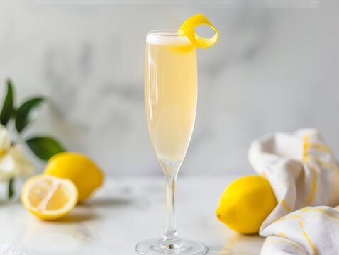 A French 75 cocktail in a champagne flute with a lemon twist on a white background