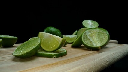 Close-up, a vibrant slice of fresh lime rests upon a rustic wooden cutting board, exuding freshness and vitality. The translucent membranes of the green lime slice placed on cutting board. Comestible.