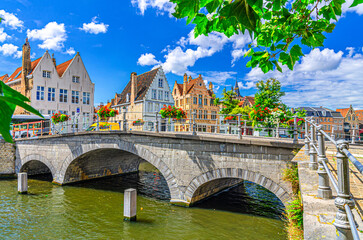 Obraz premium Bruges cityscape, Carmersbrug across Langerei water canal, arch bridge and medieval houses on promenade embankment in sunny day, Brugge old town, Bruges city historic centre, Flemish Region, Belgium