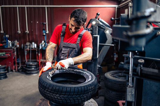 Tire repair workshop. Car mechanic mounting new car tire on the wheel.
