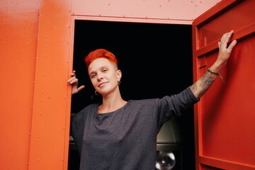 Tattooed woman looking at camera near open door and camper van