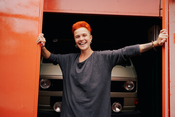 Happy woman opening garage door near camper van