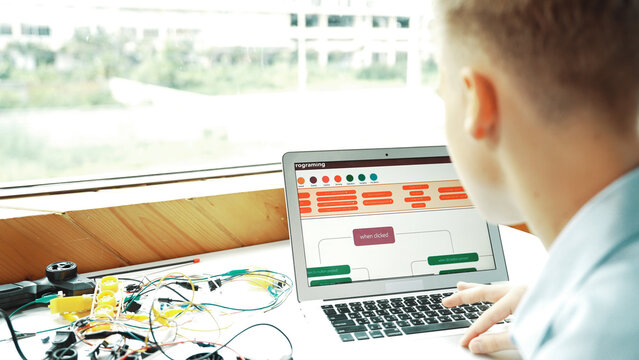 Caucasian student looking at laptop screen while coding engineering prompt or programing system. Back view of smart teenager working by using computer and electronic tool at STEM class. Edification.