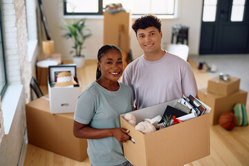 Portrait of young happy couple moving into new home and looking at camera.