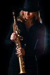 soprano saxophone in the hands of a girl on a black background