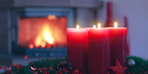 Four Advent candles on blurred fireplace background.