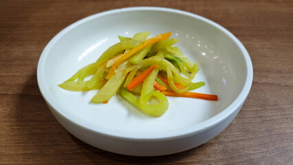 Close-up of Korean Stir-fried Zucchini and Carrot Banchan in White Ceramic Bowl on Wooden Surface