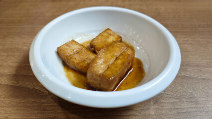 Korean Banchan with Pan-Fried Tofu Served in a White Ceramic Bowl on Wooden Table