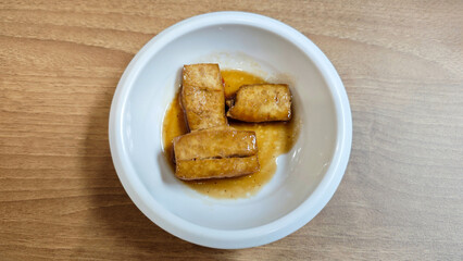 Korean Banchan with Pan-Fried Tofu Served in a White Ceramic Bowl on Wooden Table