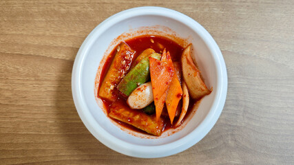 Korean Banchan with Assorted Vegetables in Spicy Red Sauce in a White Ceramic Bowl on Wooden Table