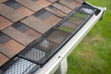 Clean roof gutter with installed mesh guard on a residential home.