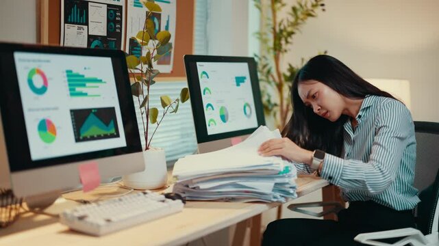 Office worker is searching for a document in a large stack of paperwork. She is becoming increasingly frustrated as she is unable to find what she is looking for