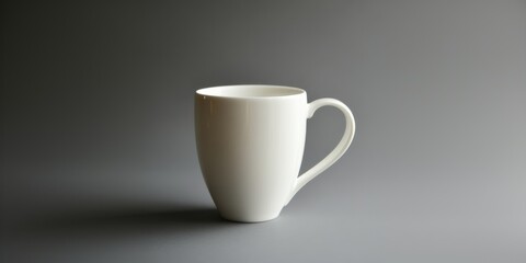 Simple white ceramic cup on a gray background in soft lighting