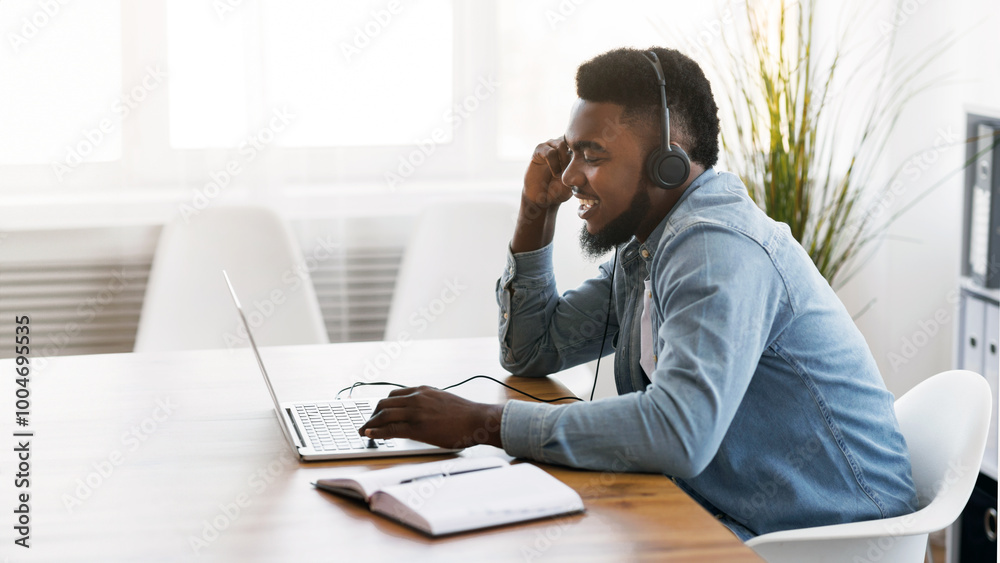 Poster customer support concept. black millennial manager with headset using laptop in office, solving clie
