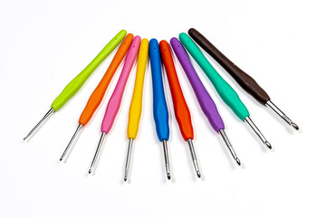 set of colorful metal crochet hooks with plastic handles in fan shape on white background