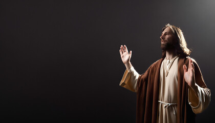 Jesus with his hands raised up on a black background © Natalia