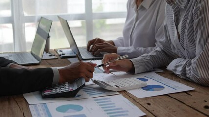 Business team collaborating and analyzing financial data with a calculator and laptop in a modern office setting