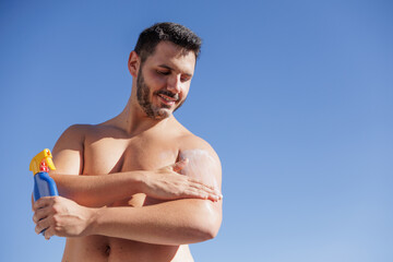 Young man applying sunscreen on his body. Protection first. Skin has memory. Preventing sun spots....