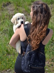Young woman walking with her golden retriever puppy in her arms. Animal adoption. Life with a dog, with a golden retriever. Protect your pets. Man's best friend.