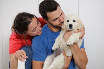 Portrait of a young couple with their golden retriever puppy. Family moments. Sharing time with loved ones. No to animal abandonment. Pets. The dog is man's best friend.