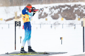 Athlete shooting in standing position at the range in a biathlon competition
