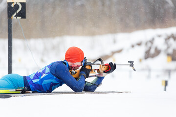 Athlete shooting in prone position at the range in a biathlon competition